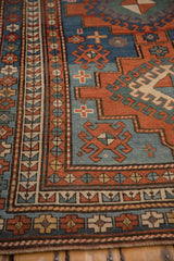 Antique Kazak rug: sapphire blue field, madder red hook motif, and geometric border.
