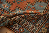 Folded antique Kazak rug detail: geometric patterns, madder root red and sapphire blue.