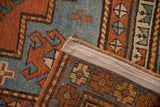 Antique Kazak rug corner revealing hand-knotted weave, madder red, sapphire blue geometric patterns.