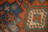 Geometric hook and latch patterns in madder red, sapphire, and powder blue on antique Kazak rug.