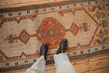 A perspective view of the vintage Serab runner's red medallion and geometric pawn motif border.