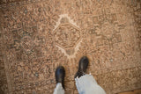 A person's view of the distressed, low-pile texture on a vintage Persian Karaja rug.