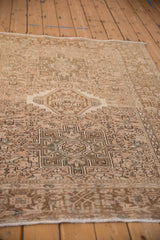 Angled view down a distressed Karaja rug showing its sandy field and geometric medallion.