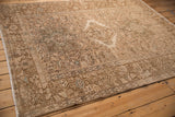 Angled view of a vintage Karaja rug featuring geometric medallions in a sandy, faded palette.