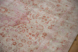 Distressed vintage rug featuring muted floral patterns in ivory and pale magenta with softened pile.