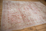 Machine bound side detail of a distressed Turkish Kaisary carpet with faded fuchsia and platinum floral patterns.