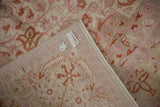 Distressed Kaisary rug pile with worn floral patterns, revealing machine bound edge and labels.
