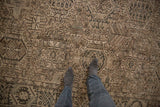 Distressed Karaja carpet showing geometric medallions, pale coffee brown tones, and worn pile.