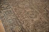 Distressed Karaja carpet detail: geometric medallions in dark olive on a pale coffee field.