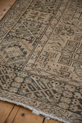 Distressed Karaja carpet section: geometric patterns in muted earthy tones, worn pile, and fringe.