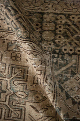 Close-up of distressed Karaja rug texture, geometric medallions, muted ivory and olive tones.