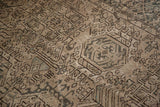 Distressed Karaja rug texture with geometric hook motifs in pale brown and dark olive.
