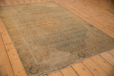 Faded dusty teal roundel border motif and distressed coffee brown surface of a Bijar rug.