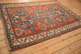 Angled perspective on a cherry red antique Kazak rug with three oversized sapphire blue medallions.