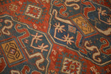 Richly textured pile of an antique Kazak rug with geometric pawn motifs in red and blue.