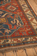 Angled view of an antique Kazak rug corner, showing the low pile and hand-knotted selvage.