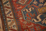 Close-up of the hand-knotted texture and pawn design border on an antique Kazak rug.
