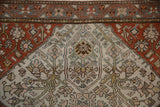 Terracotta spandrel and platinum field with interconnected vines and palmettes on an antique Malayer rug.