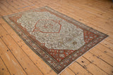 Angled perspective of an antique distressed Malayer rug with a terracotta medallion and platinum ground.