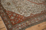 Angled view of an antique Malayer rug's terracotta border alongside its finely knotted platinum field.