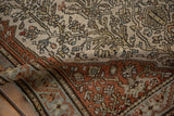 Folded corner of a distressed Malayer rug showing its hand-knotted construction and time-softened low pile.