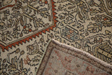 Folded corner of an antique Malayer rug showing the hand-knotted back and intact side cord.
