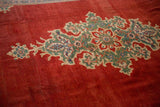 Angled view of the starburst medallion and abrashed red field of a vintage Mahal carpet.