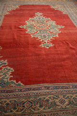 Angled perspective along the abrashed red field of a vintage Mahal carpet, showing its wool pile texture.