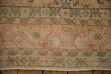 Geometric bird and floral motifs in sage and terracotta on a vintage Tabriz border.