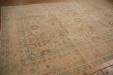 Soft, time-worn texture of a distressed Tabriz carpet with pale red and sage floral motifs.