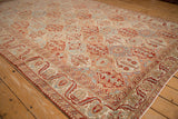 Angled view of a vintage Bakhtiari carpet showing its low, distressed pile and floral lattice.