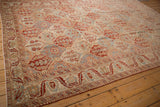 Angled view of a distressed Bakhtiari carpet's diamond lattice field and decorative border.