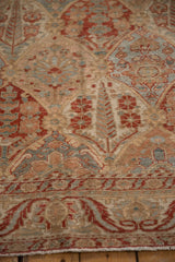 Angled view of the distressed Bakhtiari carpet's low pile, revealing cypress and floral motifs.