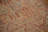 Angled view of the distressed Bakhtiari carpet's low pile, showing the serrated vine border.