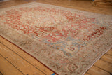 Angled view of a distressed Tabriz carpet, highlighting the worn texture and slate blue corner spandrels.