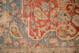 Low pile texture on a distressed Persian carpet showing sprawling vines in cherry red and slate blue.