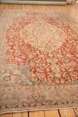 Angled view of a vintage Tabriz carpet showing the soft texture of its sprawling red and blue vines.