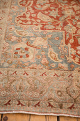 Angled view of the distressed Tabriz rug's slate blue and red corner spandrel.