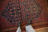 Overhead view of the vintage Malayer rug's dense Herati pattern in navy, red, and gold.