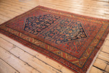 Angled perspective of a vintage Malayer rug showing its navy Herati field and red borders.
