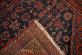Folded corner of a vintage Malayer rug showing the hand-knotted foundation and wool pile.