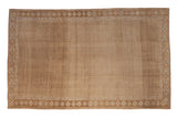 Distressed Kars carpet with an allover seed design and heavy abrashes in muted shades of beige, sand, and brown.
