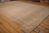 Angled view of a distressed Kars carpet's geometric border and textured, sand-colored field.