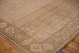 Corner detail of a vintage Kars carpet showing its geometric floral gul border and sand-colored trellis field.