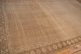 Angled view of a distressed Kars rug showing the allover trellis pattern and geometric border in sandy tones.