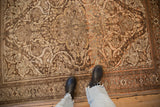 A look down at the sprawling arabesques and worn texture of a vintage Malayer rug.