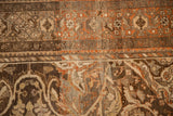 Worn, hand-knotted pile revealing terracotta, silver, and charcoal arabesque designs.