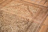 Angled view of the corner spandrel on a distressed Malayer rug showing its worn texture and sprawling arabesques.