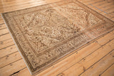 Angled view of a distressed Persian Malayer rug with a soft patina and intricate arabesque design.