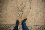 Distressed Heriz carpet with abrashed cream, sand, and faded blue geometric floral motifs.